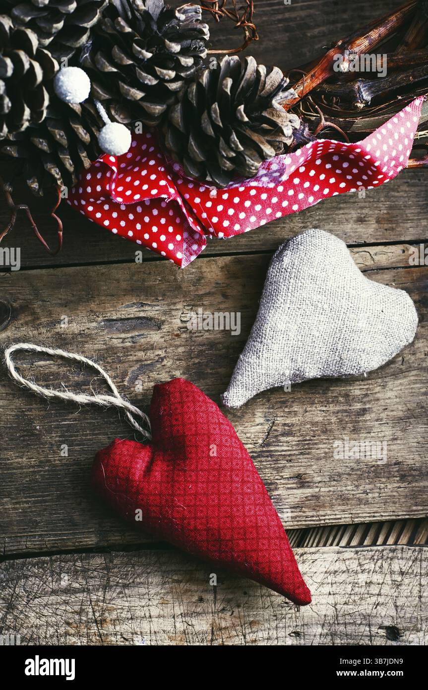 Due simboliche del tessuto del cuore ha ghirlanda di festa con pigne Foto Stock