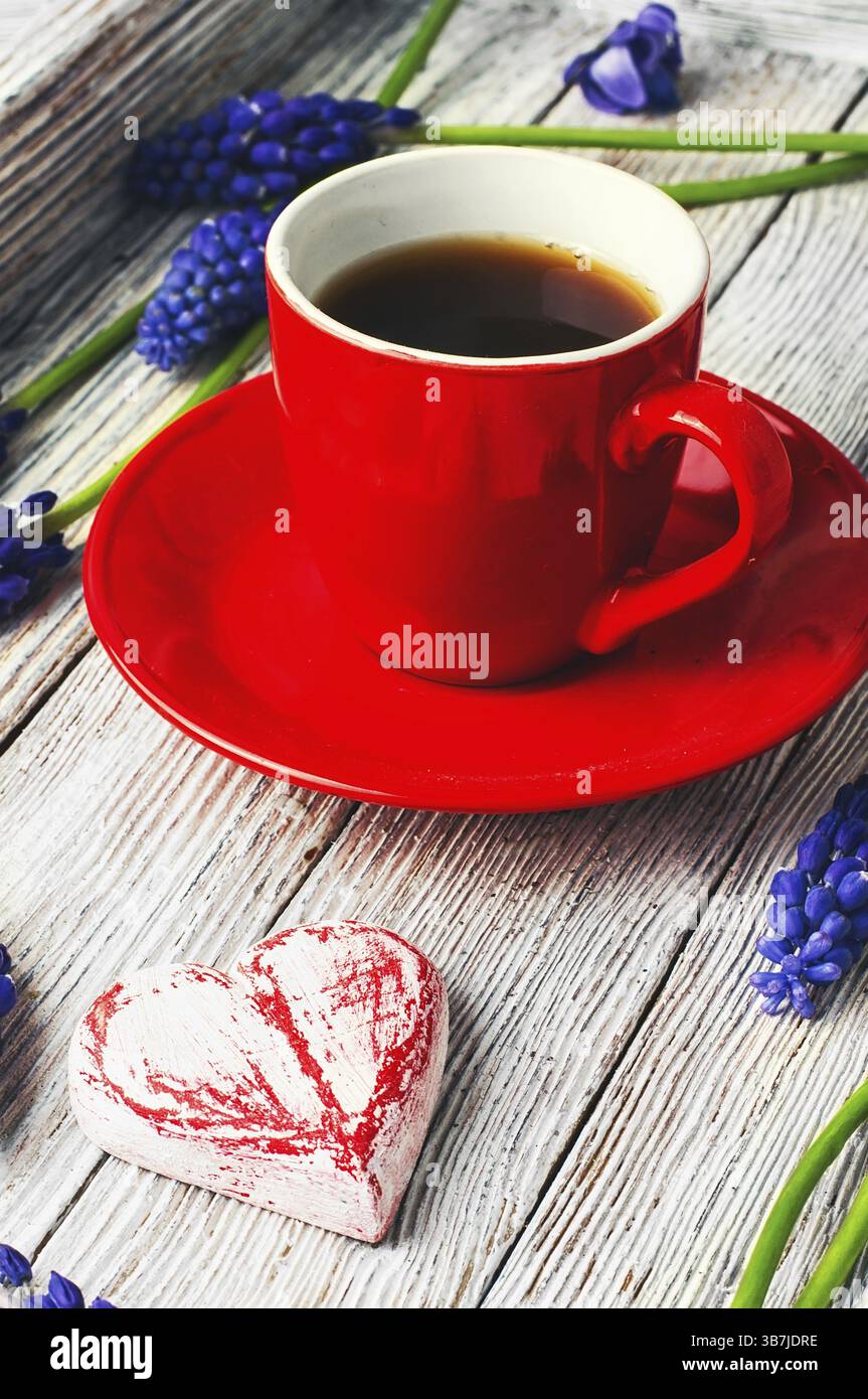 Tazza rossa con caffè, fiori, Giacinto e cuore simbolico Foto Stock