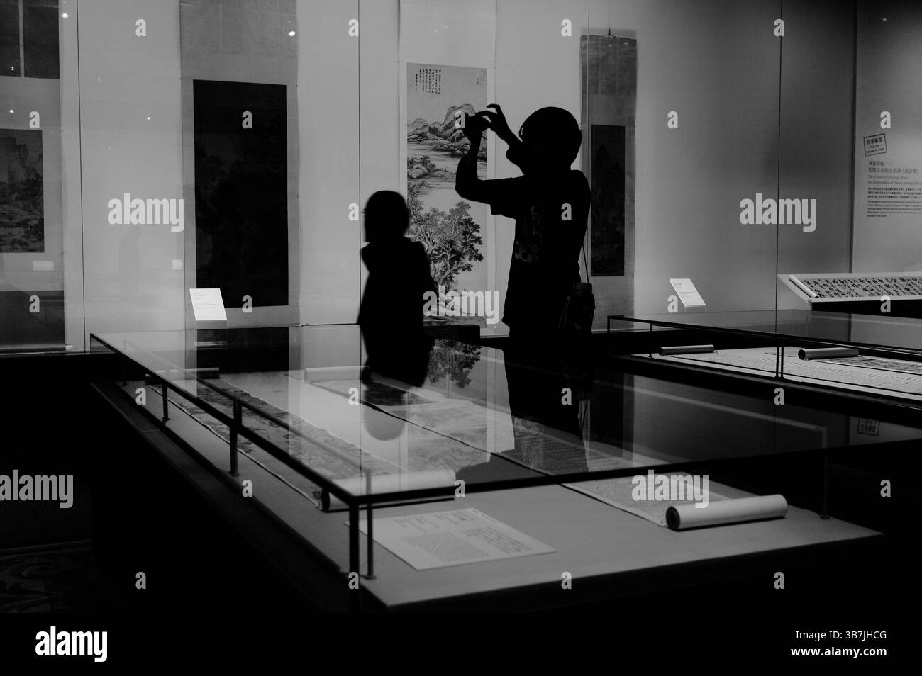 Le sagome dei visitatori del museo ammirano e documentano gli antichi dipinti a pergamena nel Museo d'Arte di Hong Kong Foto Stock