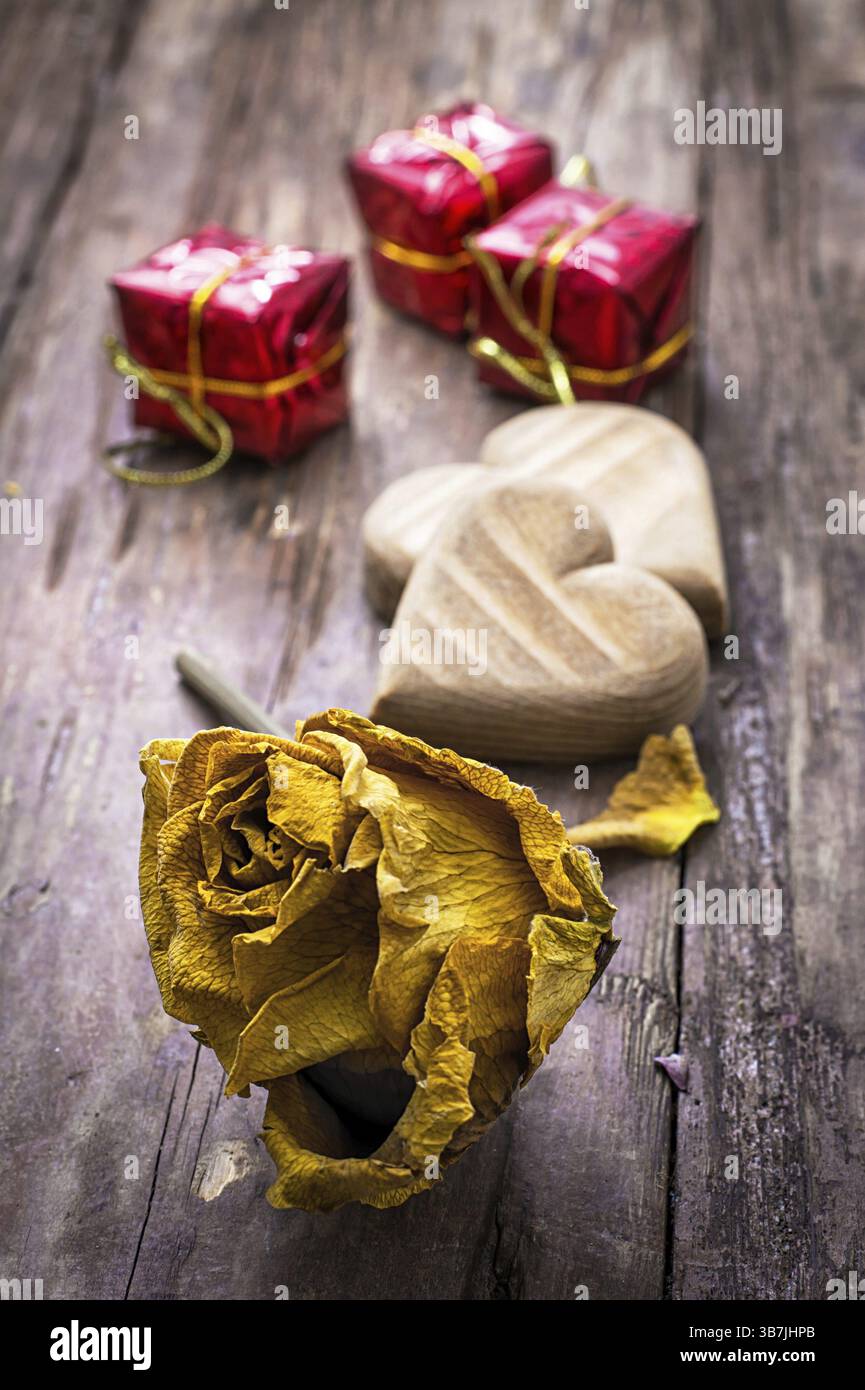 Cuore simbolico in legno intagliato a mano su uno sfondo di rose gialle Foto Stock