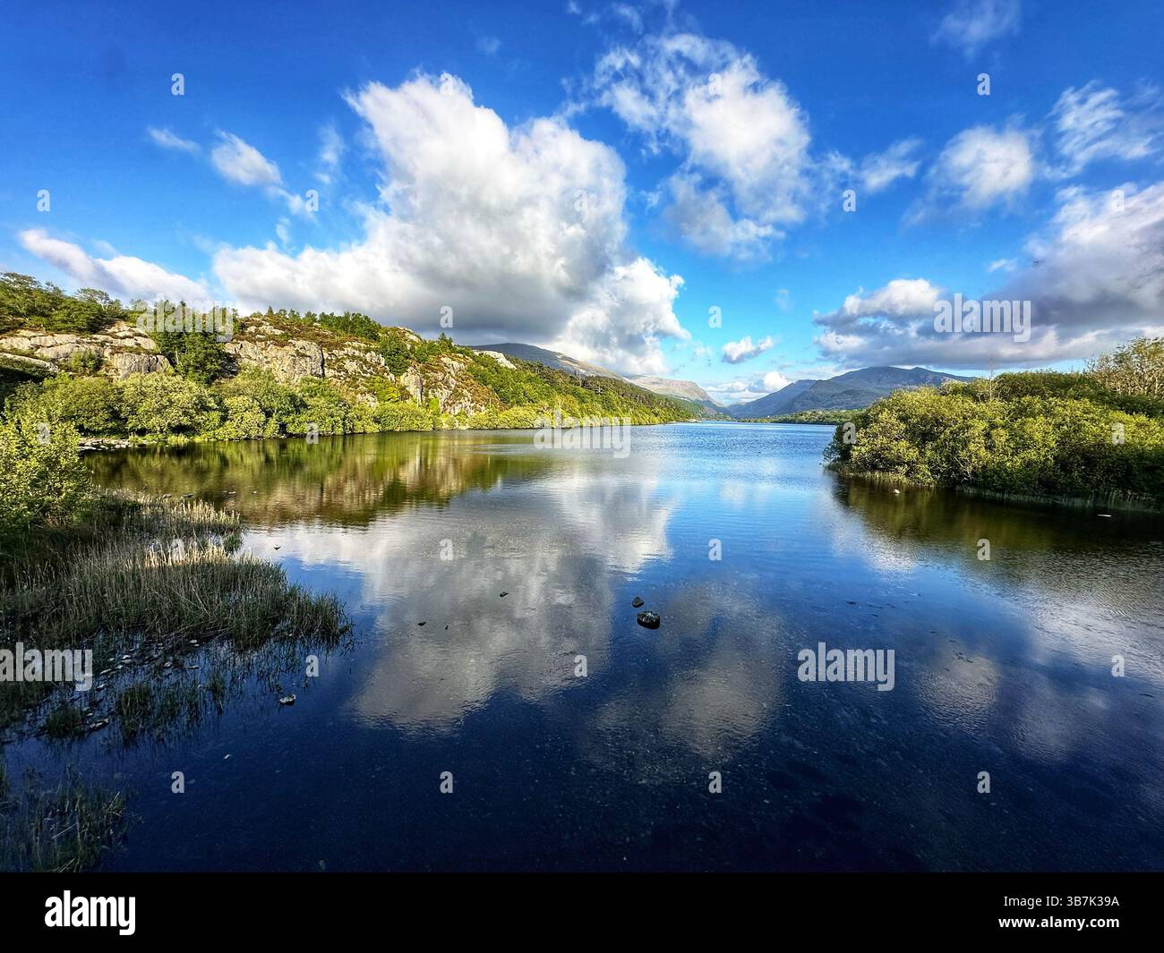 Ora d'oro sul lago Llyn Padarn nel Parco Nazionale di Snowdonia, Galles, con tranquille vedute delle acque e delle montagne. - Immagine stock catturata con smartphone