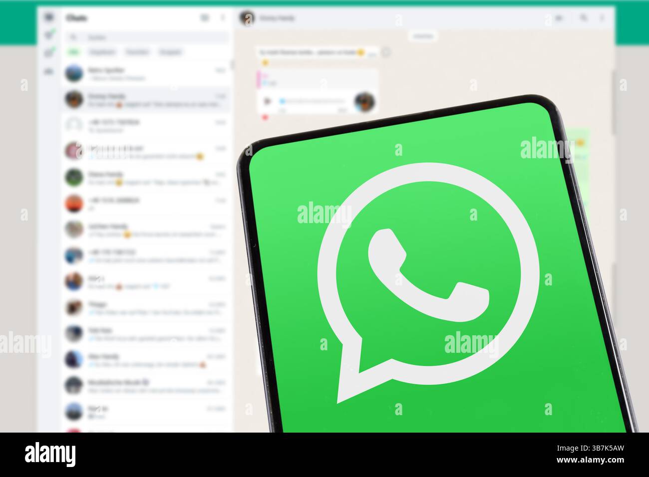 Stoccarda, Germania - 8 febbraio 2025: Applicazione di messaggistica con logo WhatsApp che invia messaggi su un telefono cellulare e un computer desktop a Stoccarda, Germania. Foto Stock