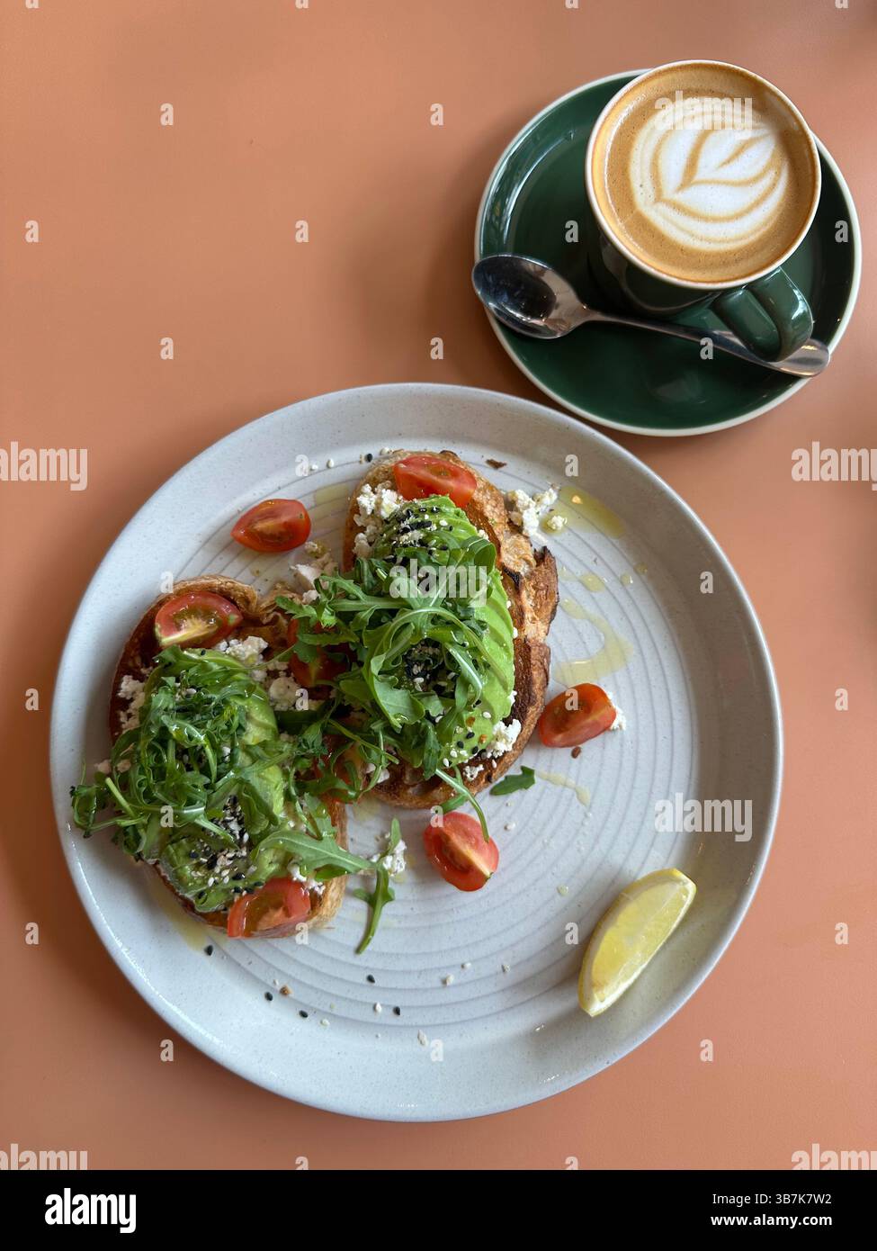 Caffè bianco piatto e toast all'avocado con limone su piatto bianco, tavolo delle pesche in posizione orizzontale. - Immagine stock catturata con smartphone