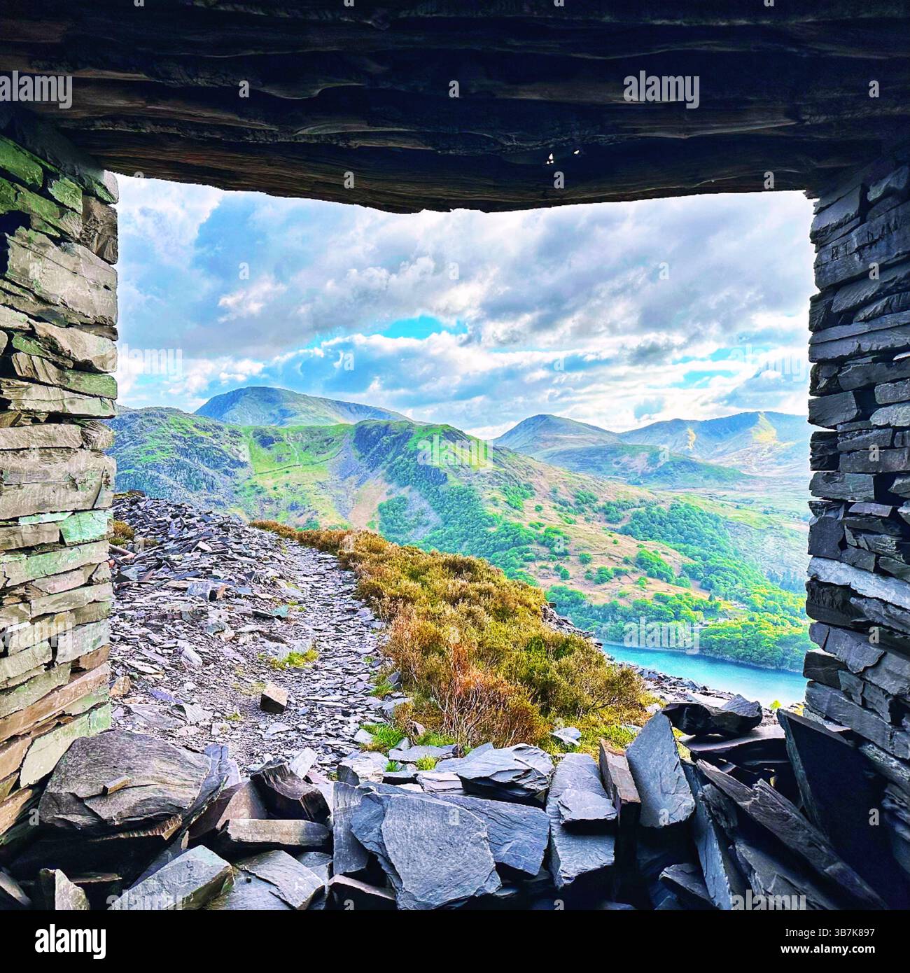 Vista incorniciata delle montagne di Snowdonia attraverso le rovine di ardesia della cava Dinorwic, Llanberis, Galles del Nord, in una luminosa giornata primaverile. Foto Stock