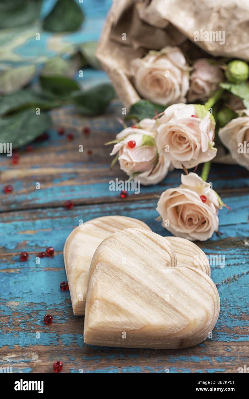 Due cuori di legno e bouquet di rose fresche Foto Stock