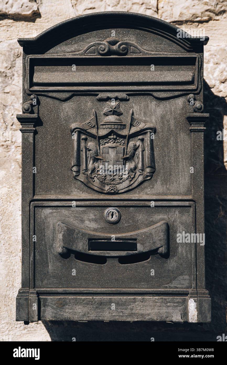Primo piano di una scatola di lettere in metallo su una parete in pietra a motivi geometrici. Foto Stock