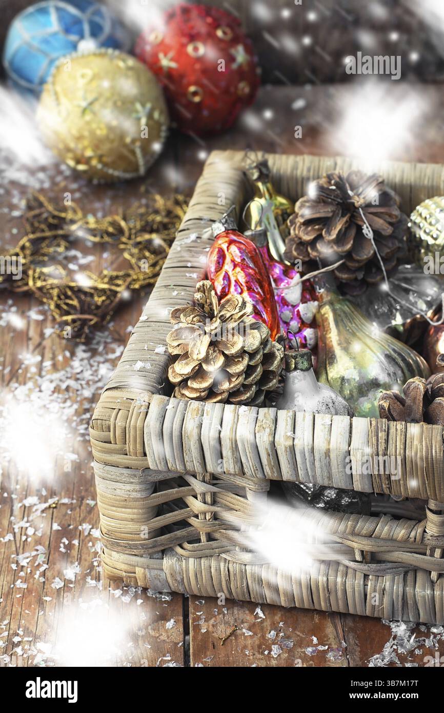 Cestino in vimini con giocattoli natalizi retrò su sfondo innevato. Neve dipinta Foto Stock