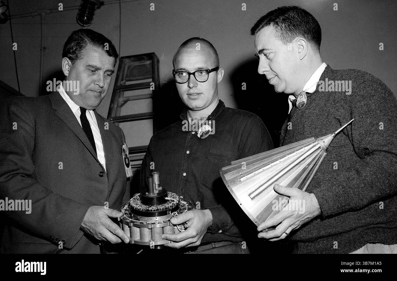Wernher von Braun era uno scienziato missilistico tedesco. Durante la seconda guerra mondiale lui e il suo team hanno studiato e perfezionato il primo razzo al mondo (il V-2). Alla fine della guerra la sua conoscenza fu ricercata sia dall'URSS che dagli Stati Uniti. Von Braun si arrese agli americani e divenne parte integrante del loro programma spaziale fino alla sua morte nel 1977. Qui viene visto (all'estrema sinistra) discutere di due componenti che costituirebbero la sonda lunare Pioneer IV. Le batterie al mercurio (a sinistra) sono state utilizzate per alimentare gli strumenti di Pioneer IV. Il convogliatore conico posto sopra gli strumenti di Pioneer IV Foto Stock