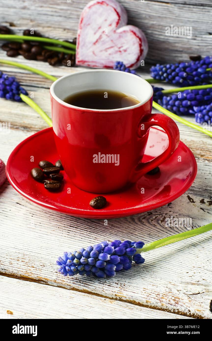 Tazza rossa con caffè, fiori, Giacinto e cuore simbolico Foto Stock