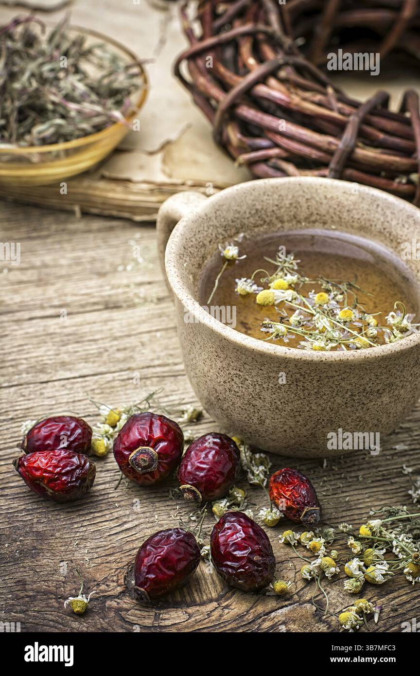 Tazza in ceramica preparata con rosa fianchi e camomilla in stile rustico vintage Foto Stock