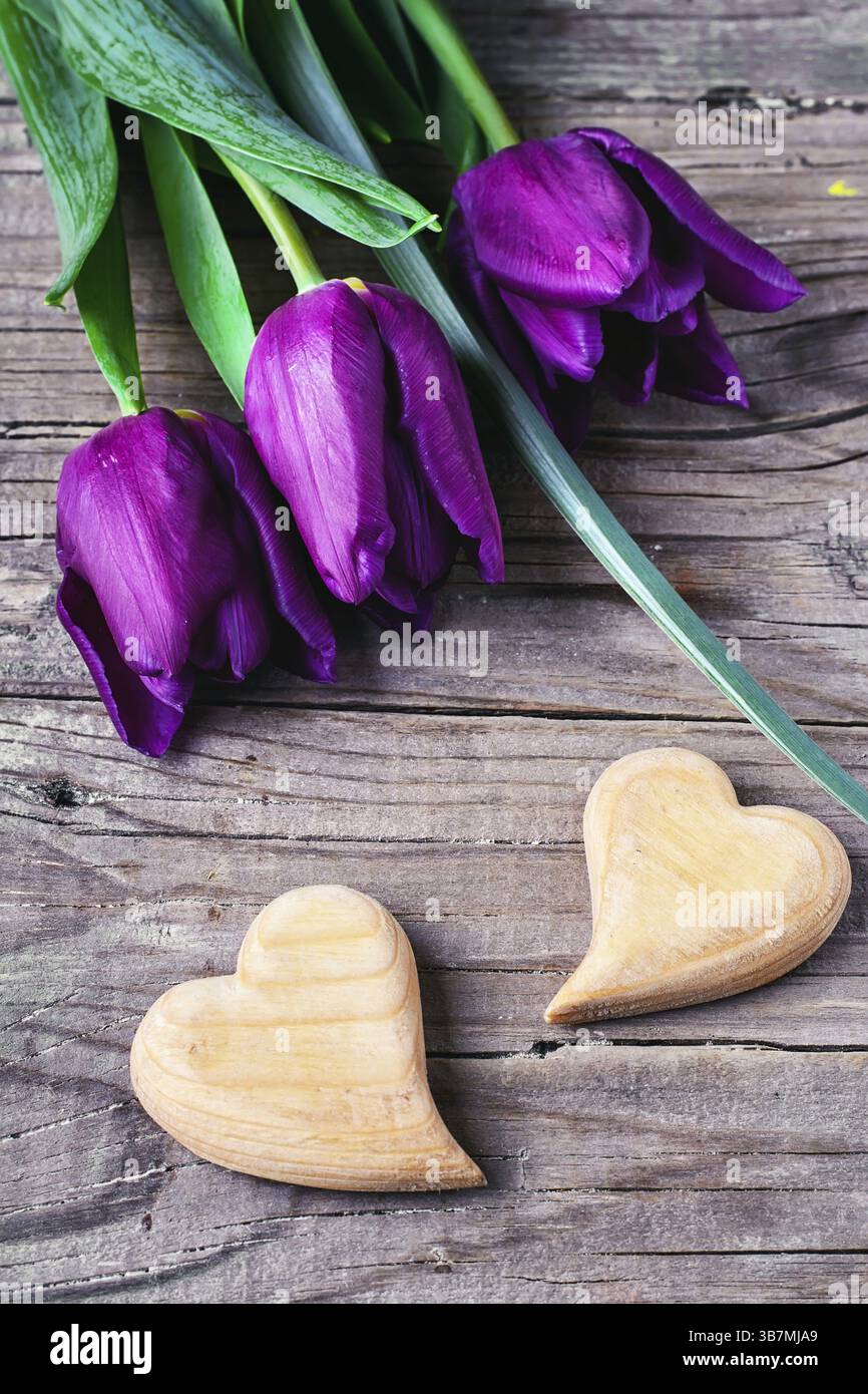 Due simbolico cuore di legno su sfondo di fiori freschi Foto Stock