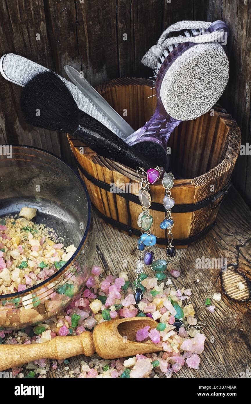 Scrub, pennello, lima per unghie in una vasca di legno sullo sfondo disseminata di sale marino per i trattamenti Spa Foto Stock
