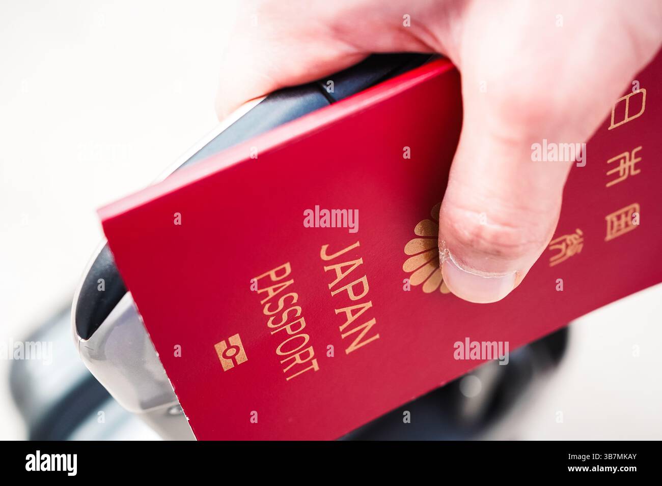 Primo piano della mano di un giovane con un passaporto e una carta d'imbarco nel mezzo, che sta per partire per un viaggio con una valigia Foto Stock