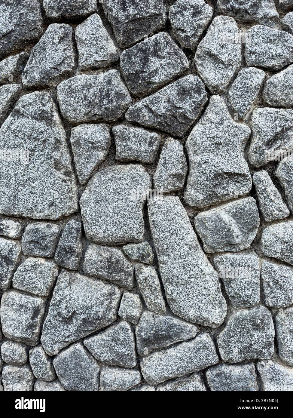 Parete in pietra grigia ruvida con struttura in muratura irregolare. Struttura rocciosa naturale utilizzata nelle superfici architettoniche, senza persone, vista ravvicinata. Foto Stock