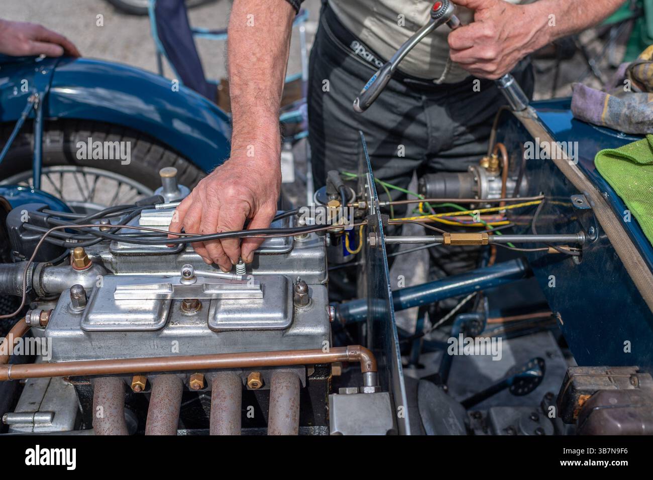 Autista e meccanico maschio che controllano le candele in un'auto sportiva Riley Brooklands d'epoca presso la V.S.C.C. Prove di velocità di Curborough. Foto Stock
