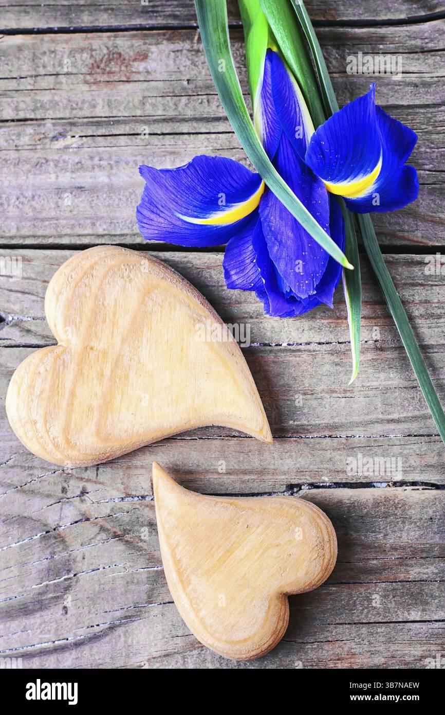 Due simbolico cuore di legno su sfondo di fiori freschi Foto Stock