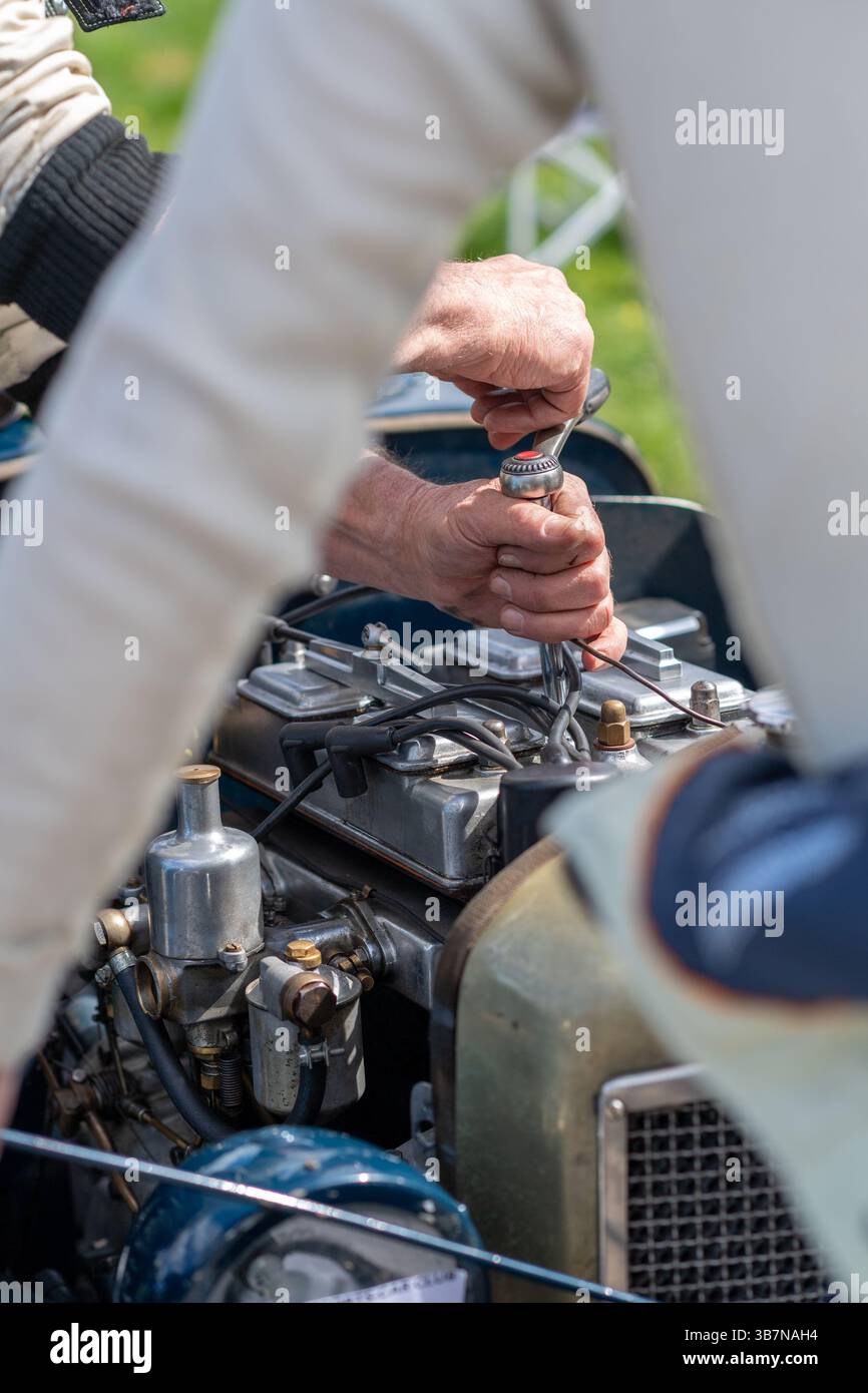 Autista e meccanico maschio che controllano le candele in un'auto sportiva Riley Brooklands d'epoca presso la V.S.C.C. Prove di velocità di Curborough. Foto Stock