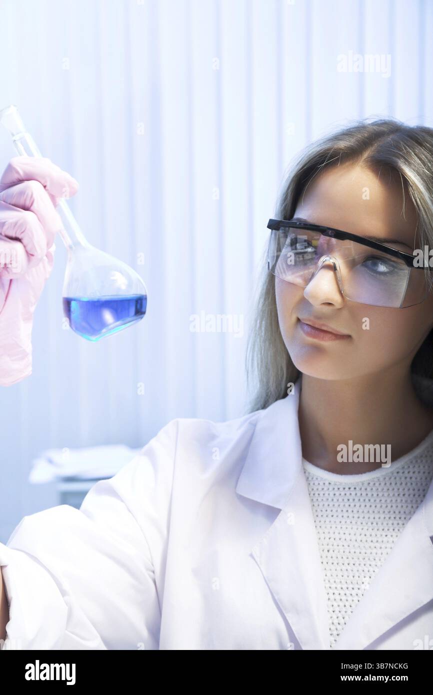 Ricercatrice femminile guarda la storta con liquido blu Foto Stock