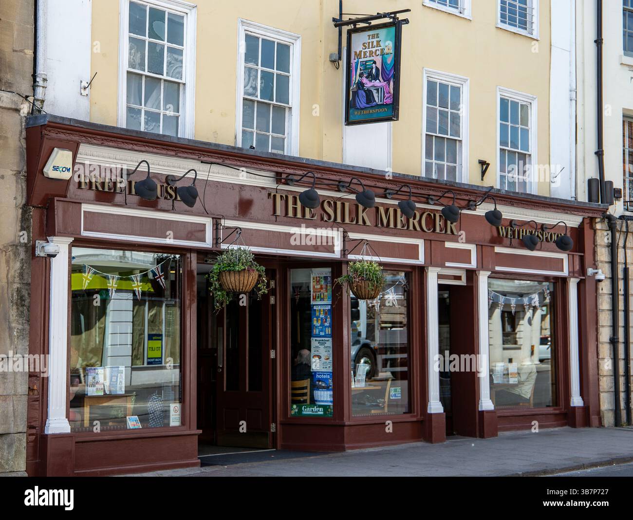 Facciata di un pub Wetherspoons, il Silk Mercer, in un edificio storico con piante appese e grandi finestre in una giornata di sole a Devizes Wiltshire. Foto Stock