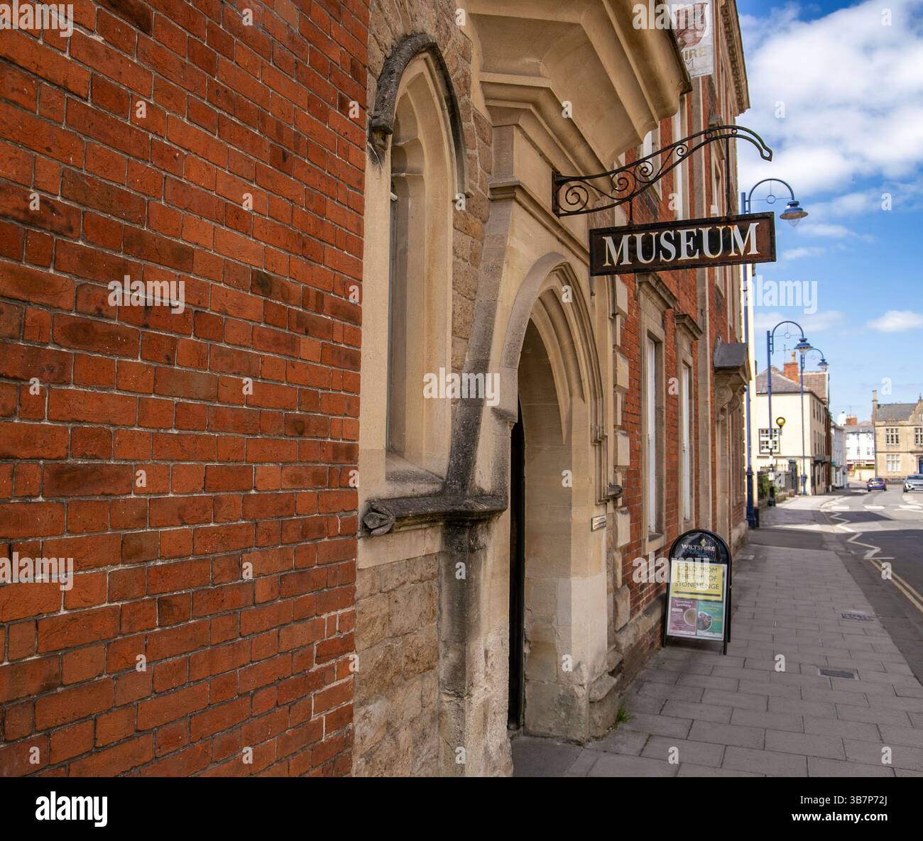 Ingresso al museo Devizes con un cartello vintage su una facciata di un edificio in mattoni lungo una pittoresca strada urbana Foto Stock