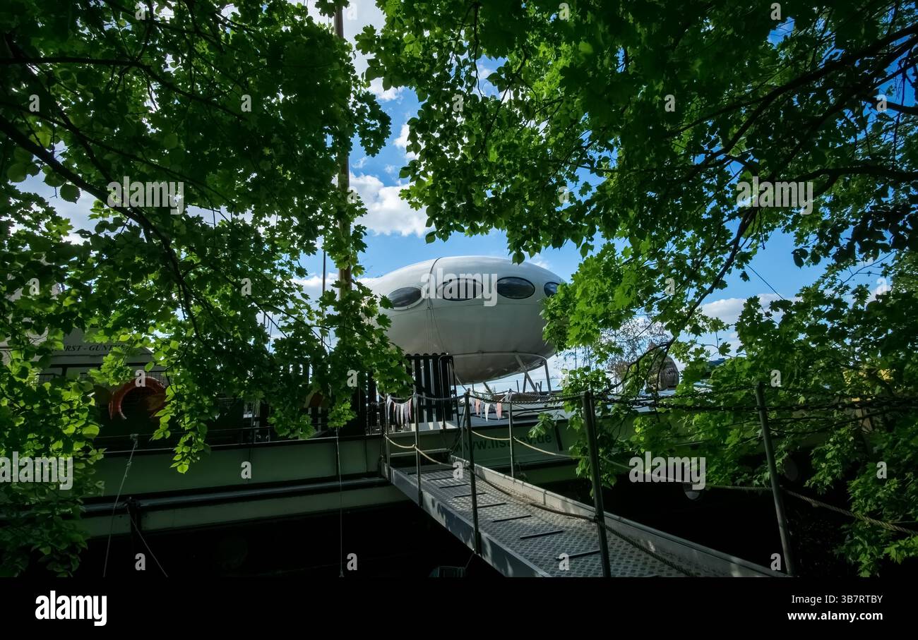 Futuro House a forma di UFO sul ponte della nave MS Heimatland, ormeggiata a Treptower Hafen vicino a Insel der Jugend a Berlino, circondata da alberi. Foto Stock