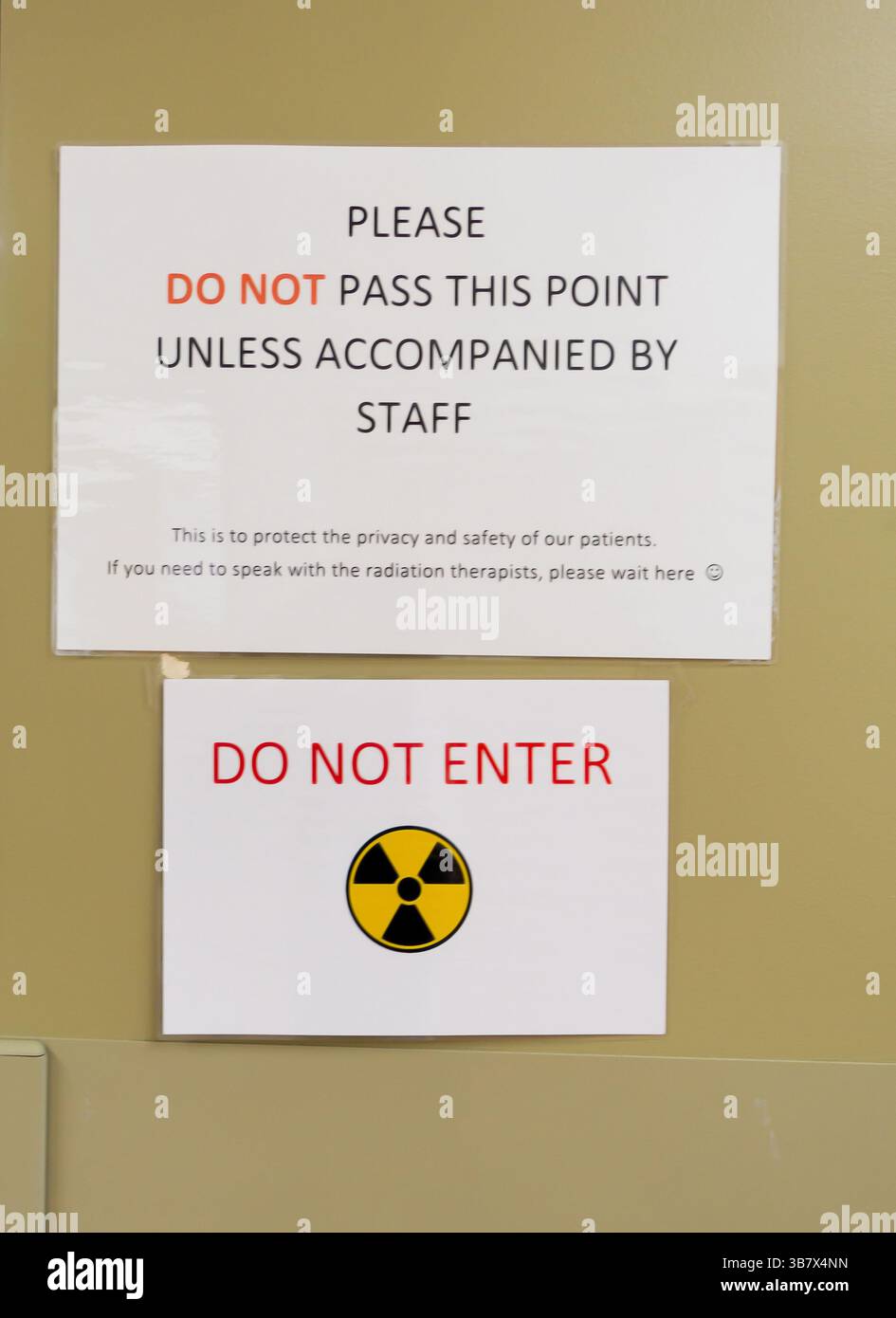 Il cartello su una porta che avverte del pericolo di riassegnazione include il simbolo internazionale delle radiazioni. Foto Stock