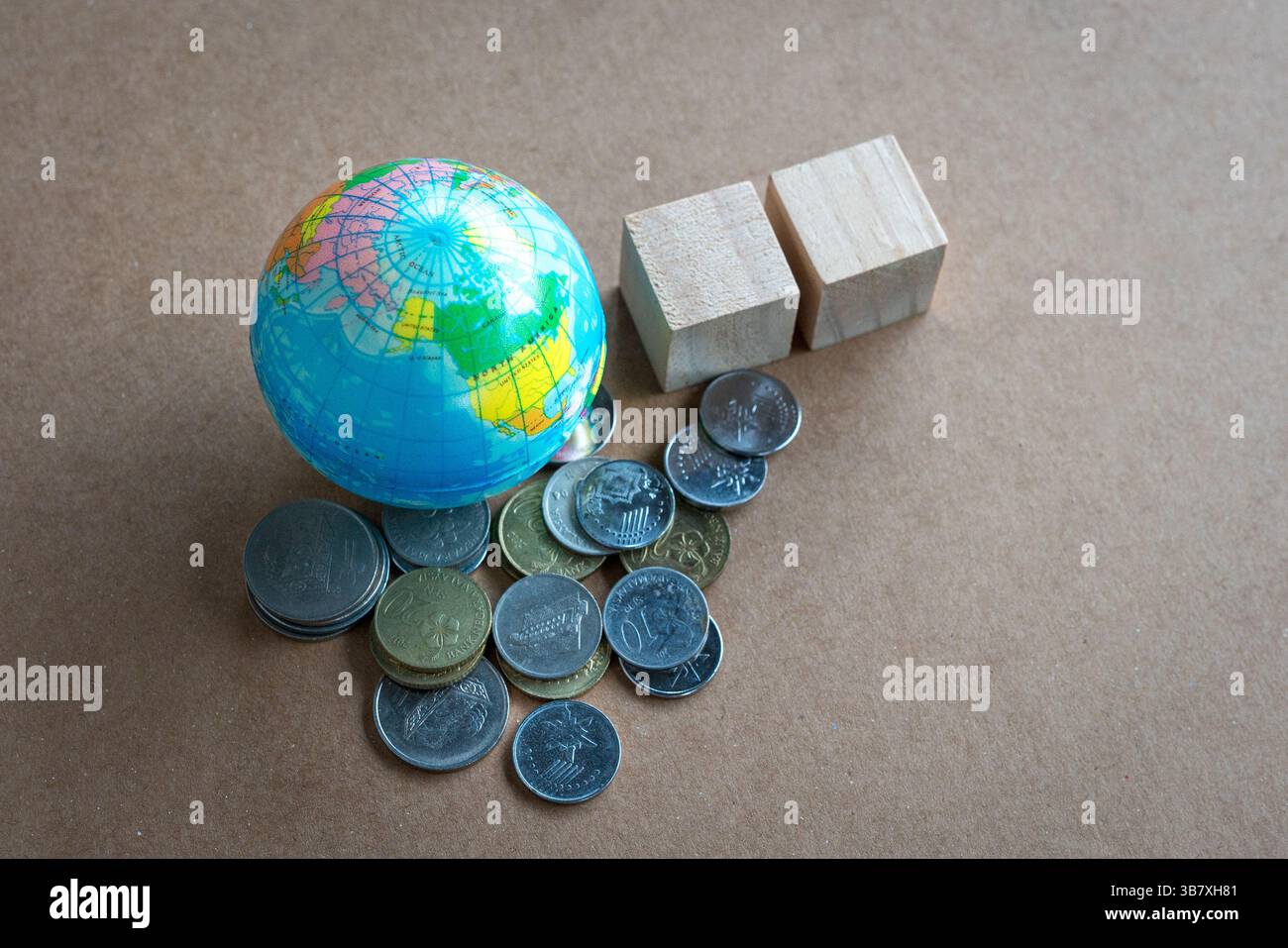 Globo con un mucchio di monete e due blocchi di legno quadrati. Vista ad angolo alto. Foto Stock