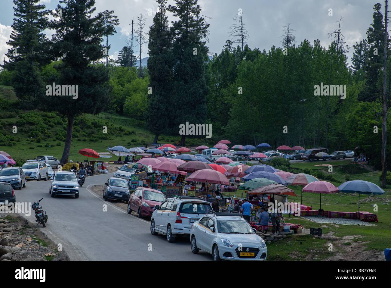 23 maggio 2024, Doodhpathri, Jammu e Kashmir, India: I veicoli sono parcheggiati lungo una strada mentre i turisti e la gente del posto si godono il Noon Chai (tè salato) con tortillas di farina di mais in una stalla lungo la strada Doodhpathri nel distretto di Budgam, a sud-ovest di Srinagar. Le autorità hanno chiesto ai proprietari dei venditori di tè di liberare lo spazio che hanno occupato ''illegalmente'' entro dieci giorni o di affrontare azioni. I funzionari hanno detto a un'agenzia di stampa locale che l'autorità per lo sviluppo del turismo ha ricevuto numerose lamentele per il fatto che i proprietari delle bancarelle di tè hanno tagliato rami di alberi, danneggiando così il quadro Foto Stock