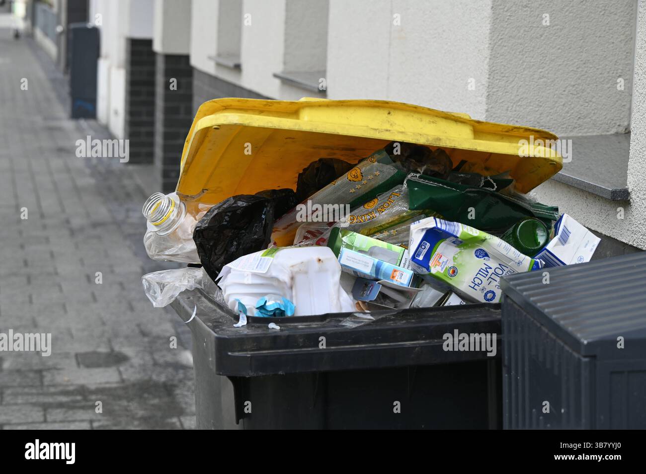 gelbe tonne, voll, mit gesammelten Muell aus Kunstoff, Metall oder Verbundmaterialien mit gruenen Punkt steht am Strassenrand zur Abholung bereit *** la spazzatura gialla, piena, con rifiuti raccolti in plastica, metallo o materiali compositi con un punto verde è pronta per la raccolta in strada Foto Stock