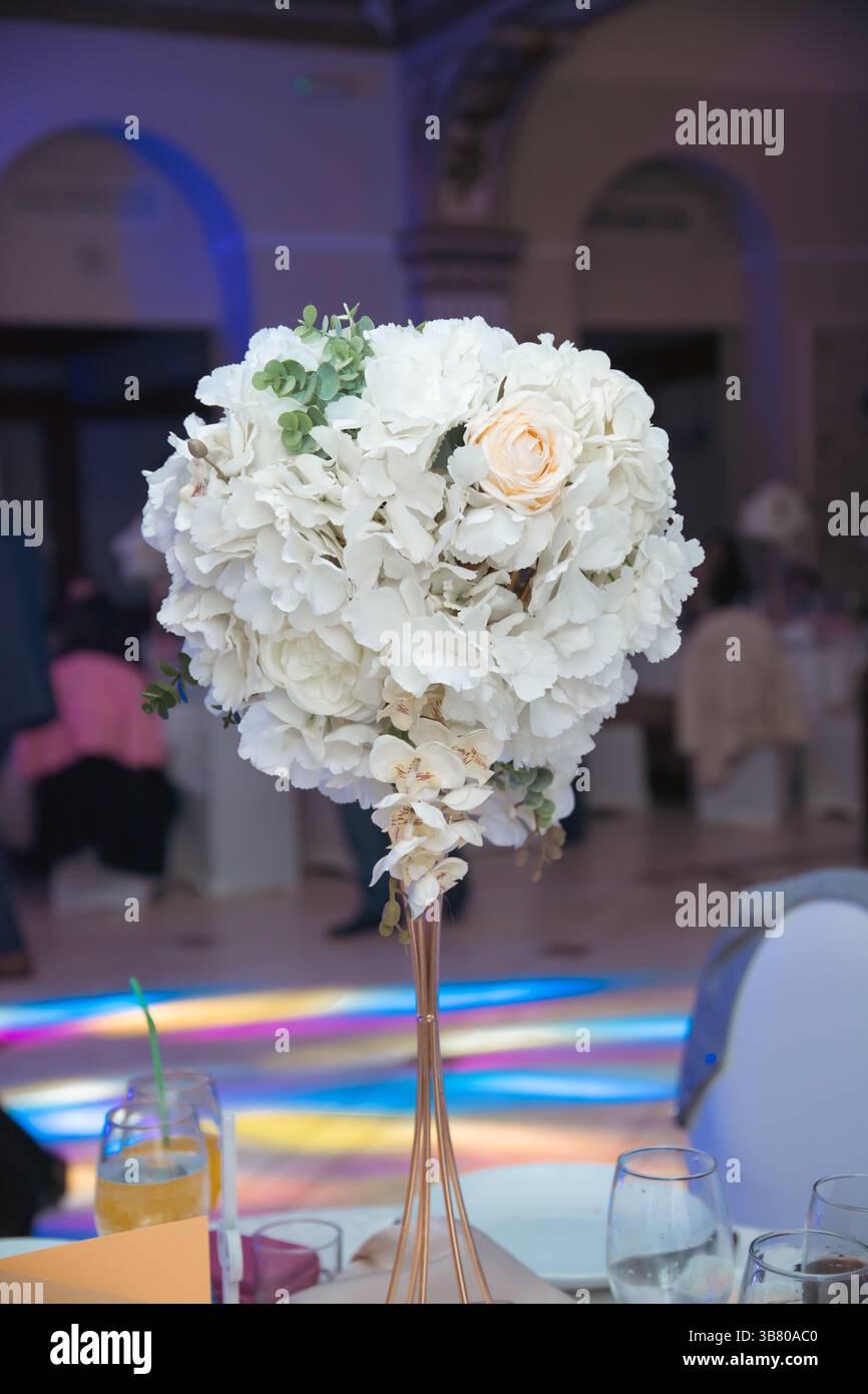 Tavolo per ricevimenti nuziali con piatti e bevande decorato con un vaso di fiori. Foto Stock