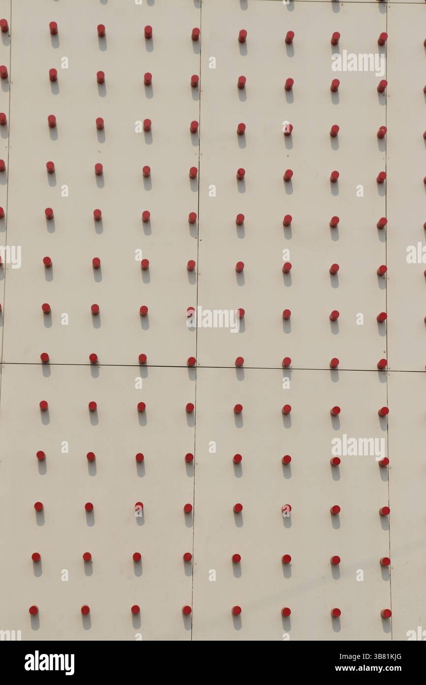 La vista dettagliata rivela un modello regolare di piccoli cilindri rossi fissati su una superficie bianca pulita, che mostrano una disposizione deliberata e ordinata con Foto Stock