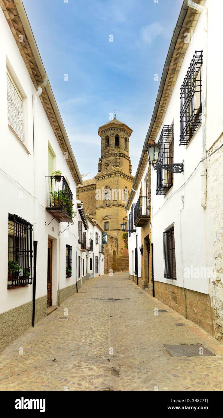 Una strada stretta con un alto edificio sullo sfondo. La strada è fiancheggiata da edifici bianchi e ha una superficie acciottolata. Vicolo con tipici e. Foto Stock