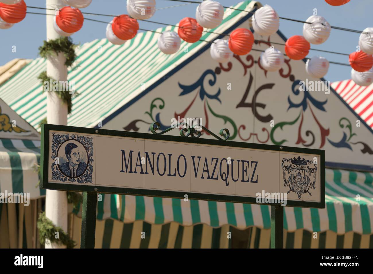 Insegna di via Manolo Vázquez decorata con piastrelle durante la Feria de Abril di Siviglia, Andalusia, Spagna, sotto lanterne colorate. Siviglia, Spagna Foto Stock