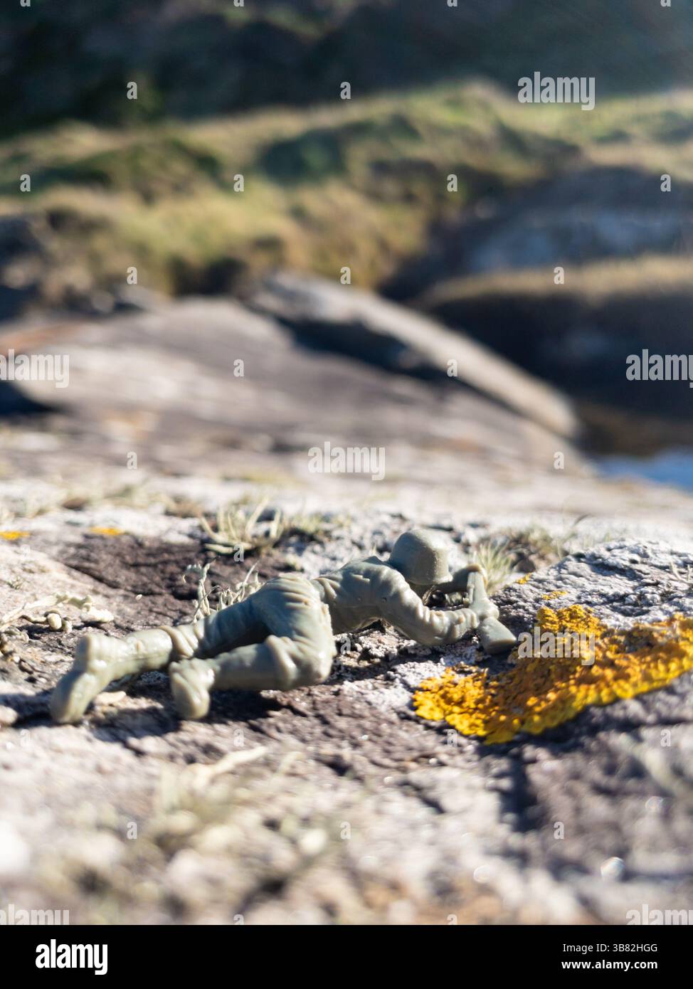 Soldato giocattolo di plastica disteso su roccia all'aperto fucile di mira Foto Stock