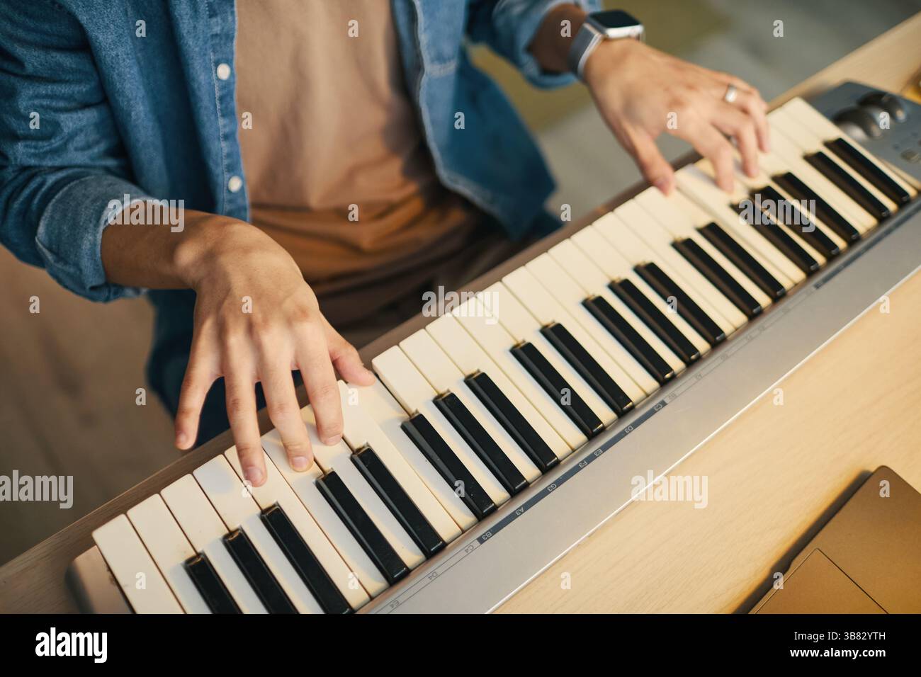 Vista ravvicinata delle mani maschili che suonano abilmente melodie sulla tastiera elettrica. La composizione dettagliata mostra le dita che creano musica su tasti in bianco e nero Foto Stock
