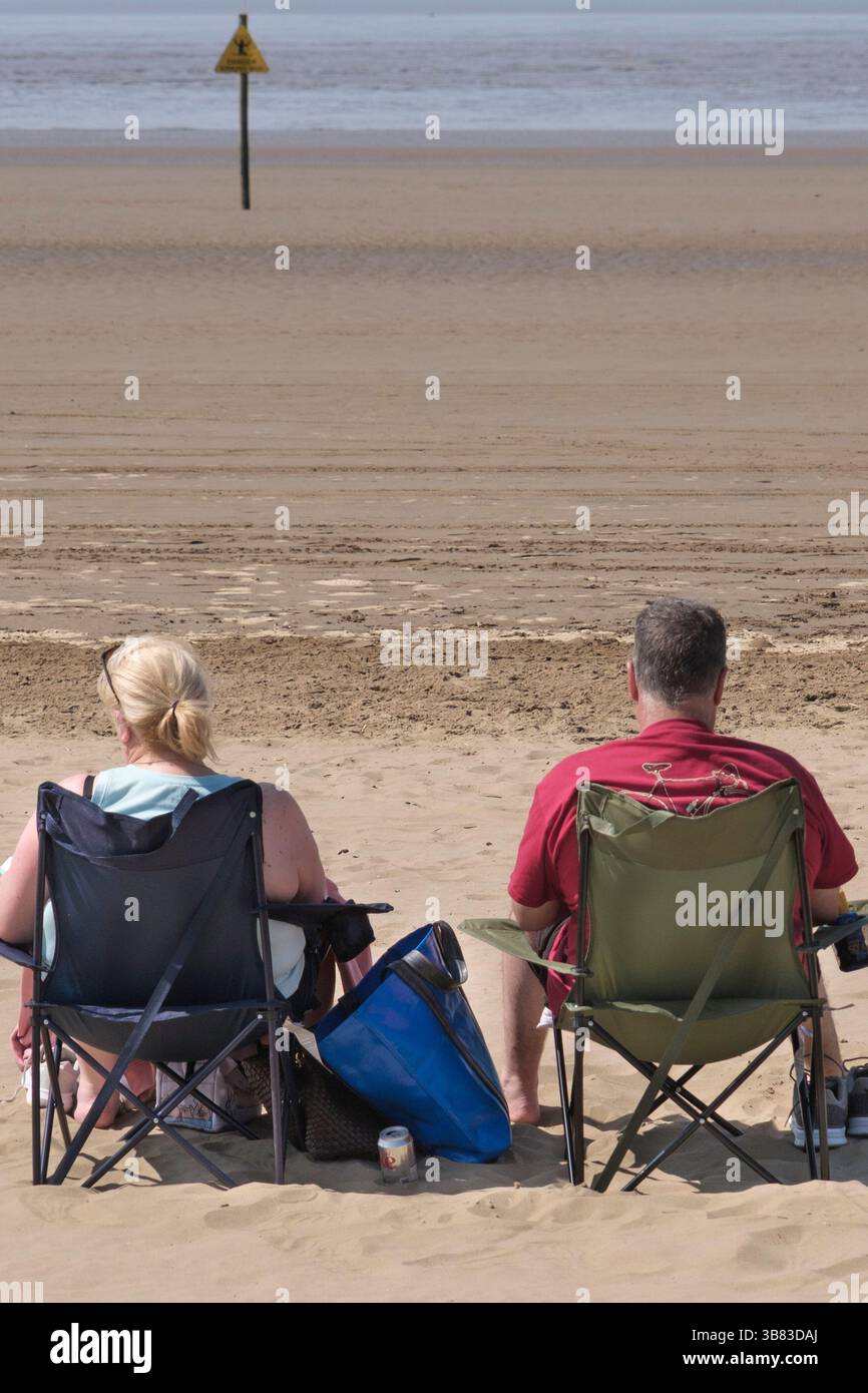 due persone sedute sul lungomare di weston-super-nare si godevano le sedie a sdraio sul mare; sedie pieghevoli; Foto Stock