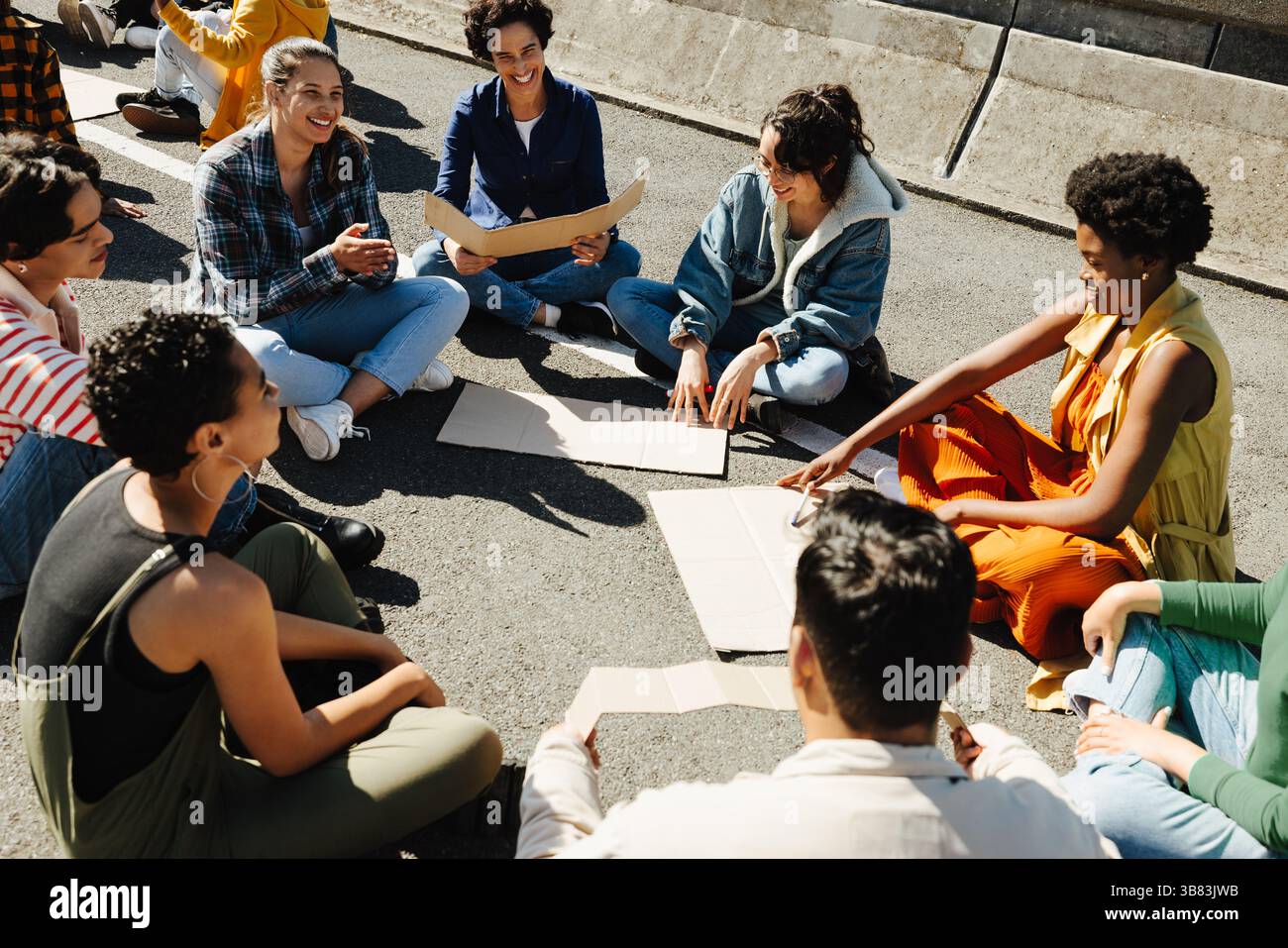 La luce calda del sole splende su un gruppo eterogeneo di persone sedute insieme a discutere la loro causa in unità e ottimismo. Rappresentano un forte senso di co Foto Stock