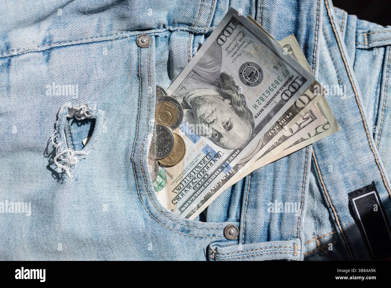 I soldi 100 dollari e le monete sono in Jeans lacerati nella tasca. Crisi mondiale, concetto. Inflazione Foto Stock