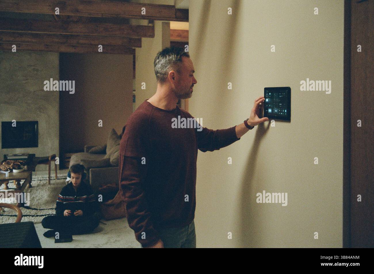 Uomo che regola la temperatura della casa tramite l'app Smart Home a casa Foto Stock
