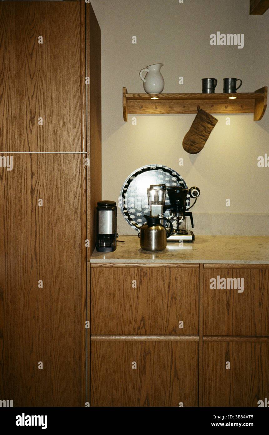 Macchina per il caffè sul banco della cucina con armadietti in legno Foto Stock