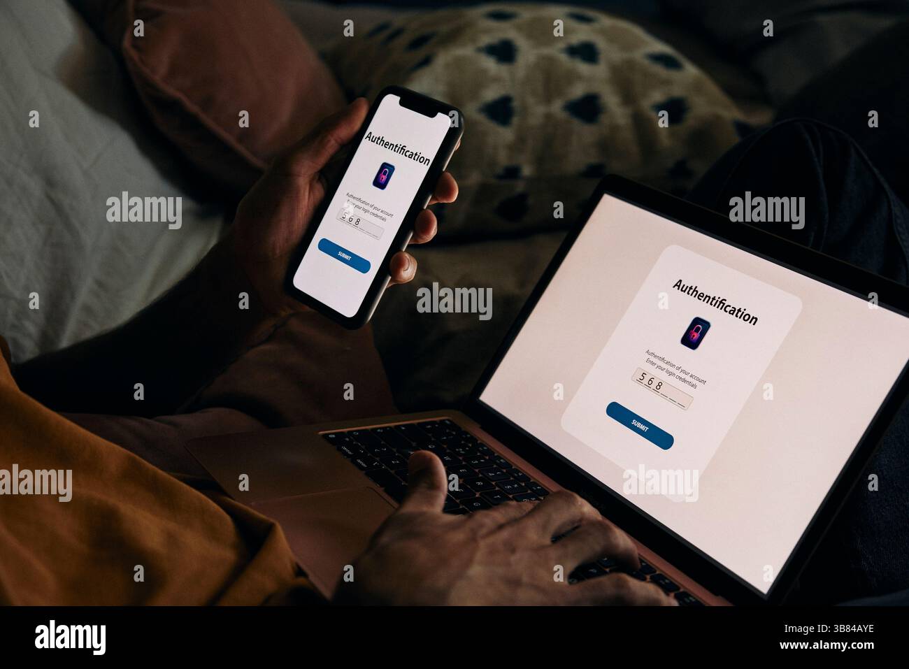 Intersezione dell'uomo che digita la password sul laptop per l'autenticazione tramite smartphone a casa Foto Stock