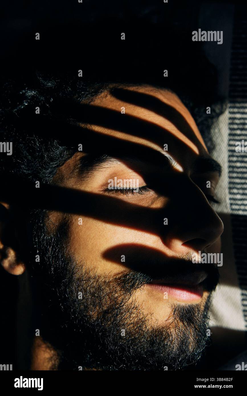 La luce del sole splende sul volto dell'uomo che dorme a casa Foto Stock