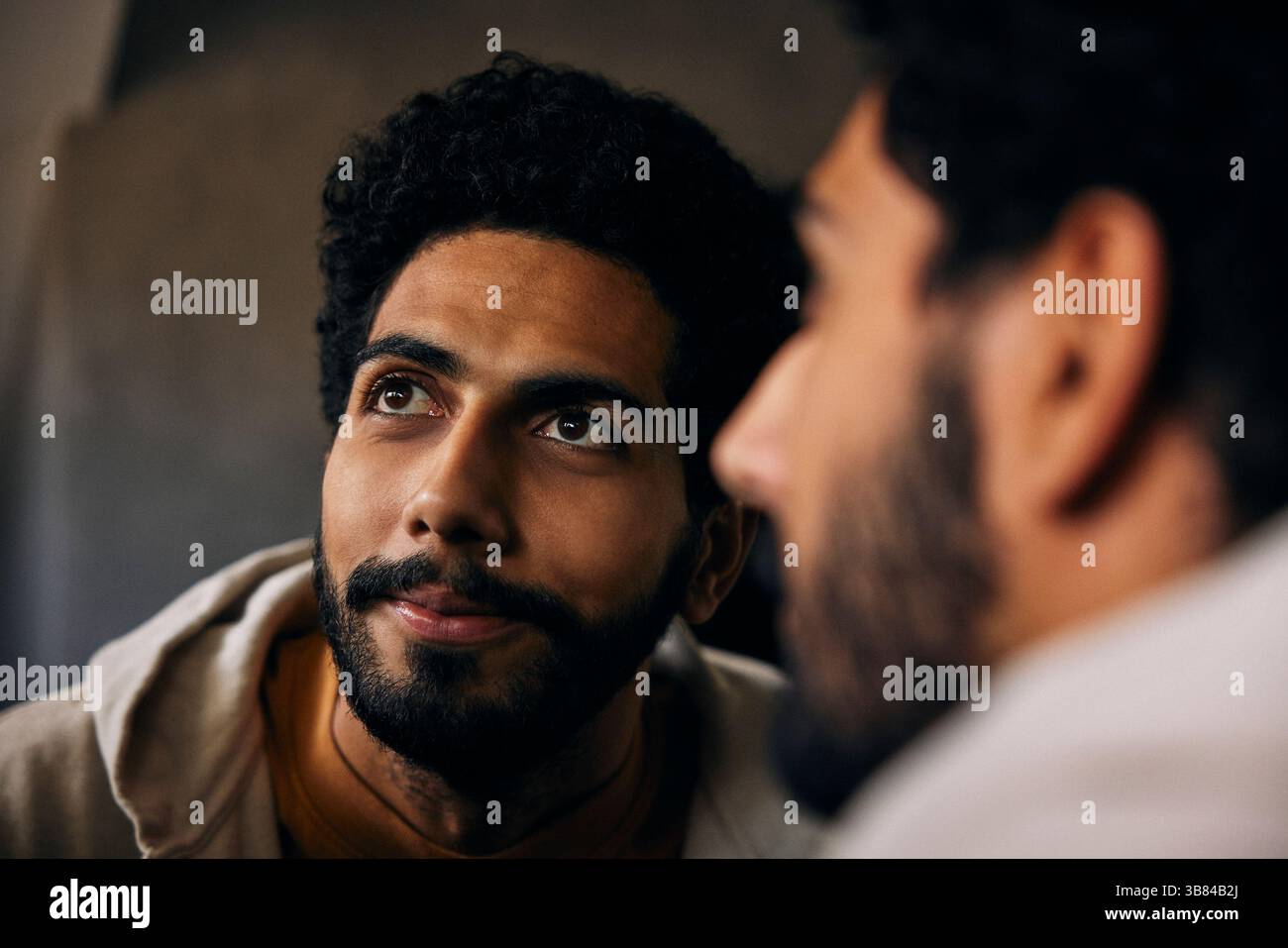 Specchio riflesso dell'uomo con capelli ricci che guardano lontano Foto Stock