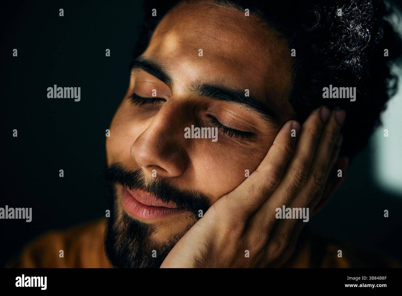 Uomo sorridente con gli occhi chiusi appoggiati sul palmo della mano Foto Stock