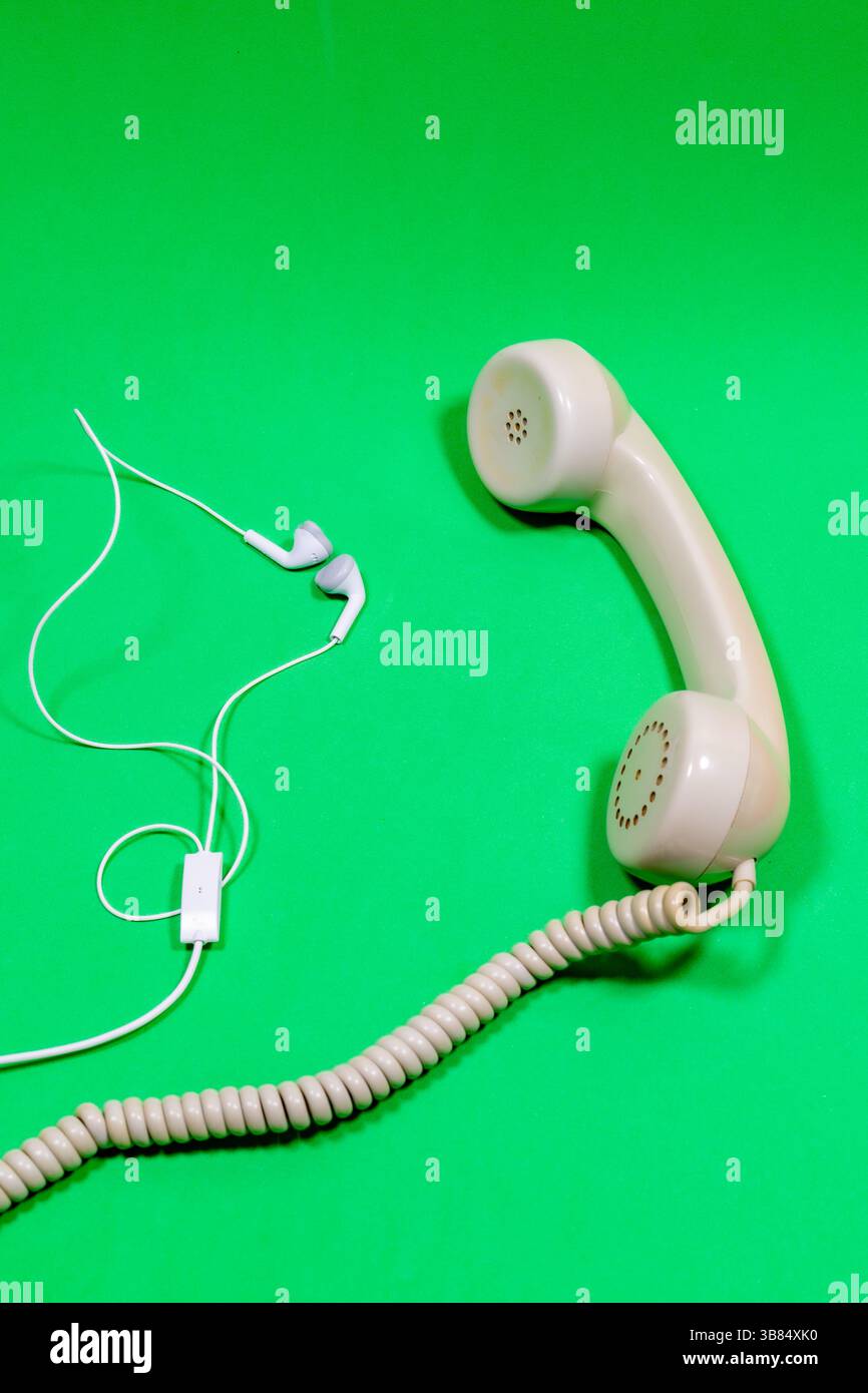 Ricevitore telefonico meno recente con un nuovo ricevitore più piccolo su una superficie verde. Foto Stock