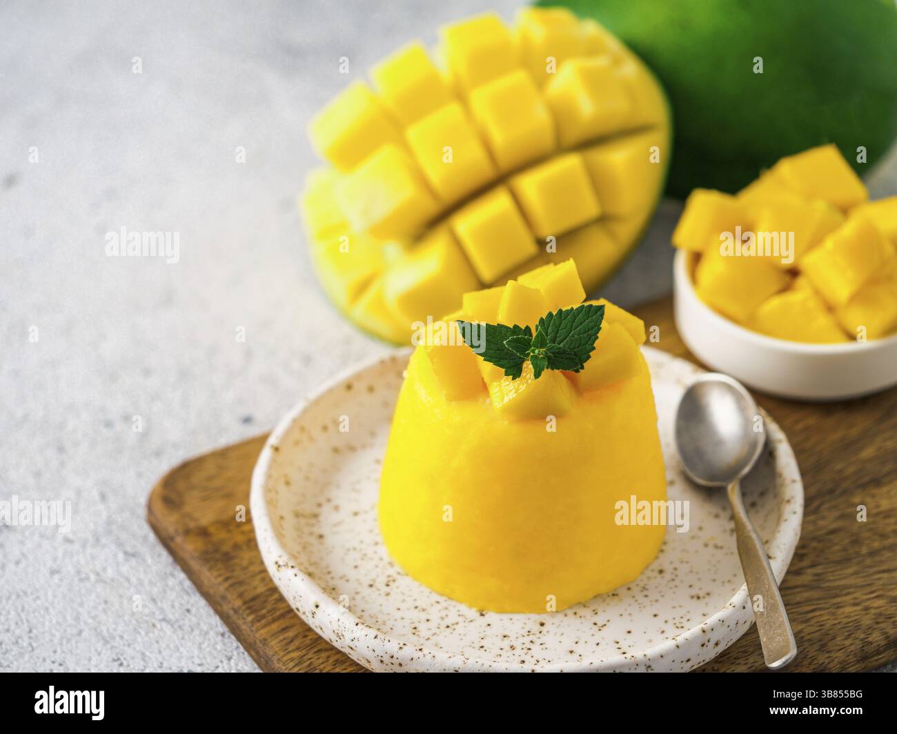Mousse di mango sul cemento grigio Sfondo con copia spazio a sinistra. Giallo mango mousse con fette di mango maturi Foto Stock