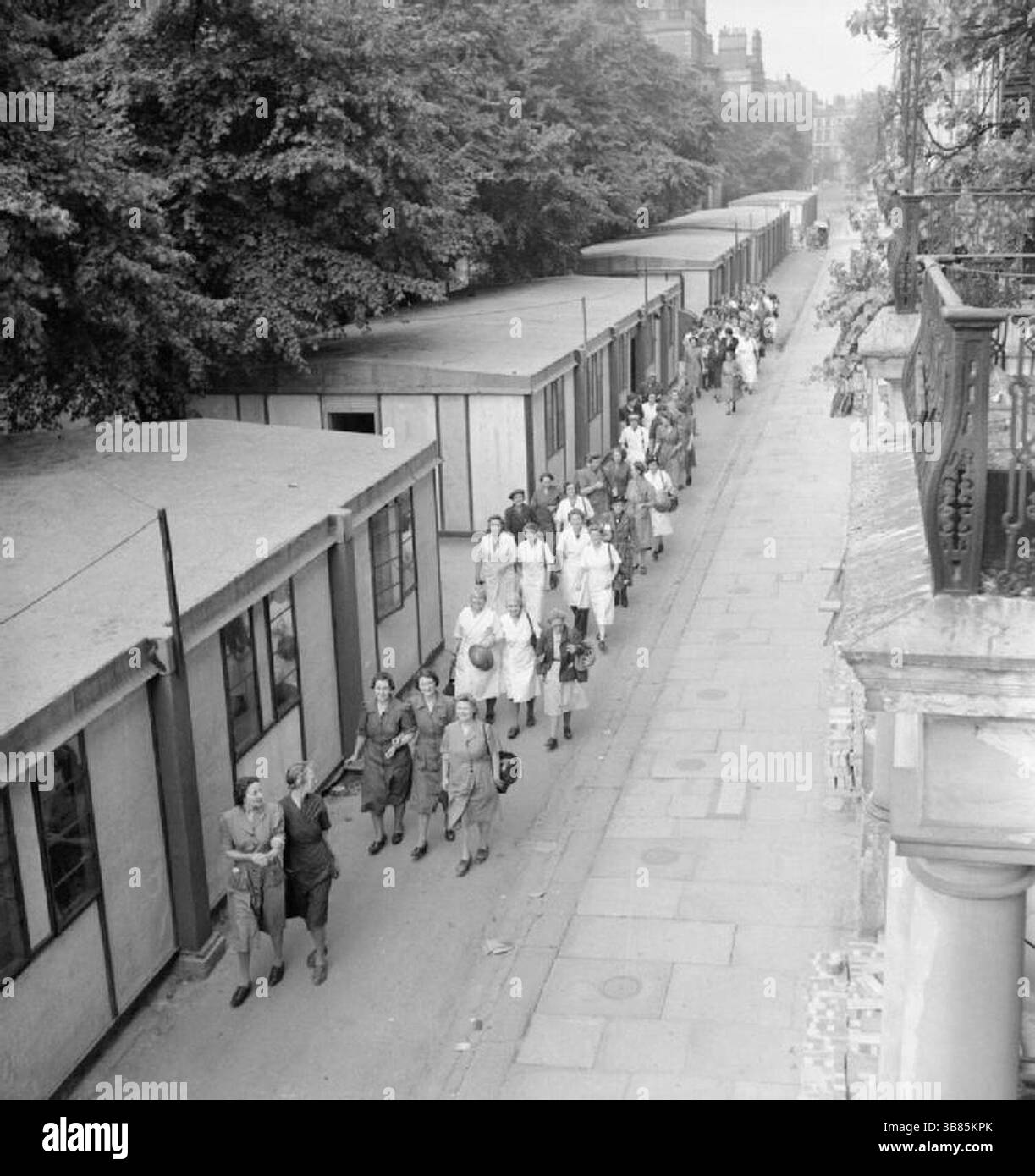 Le donne del Women's Voluntary Service (WVS) arrivano presto per preparare la colazione per gli uomini della "Blitz Repair Squad", una squadra di costruttori che sono venuti a Londra da varie parti del paese per aiutare a riparare i danni causati dalle bombe volanti V1. Le donne possono essere viste passeggiare davanti ad alcuni dei disordini e rifugi costruiti lungo la strada in Onslow Square a Londra. Foto Stock