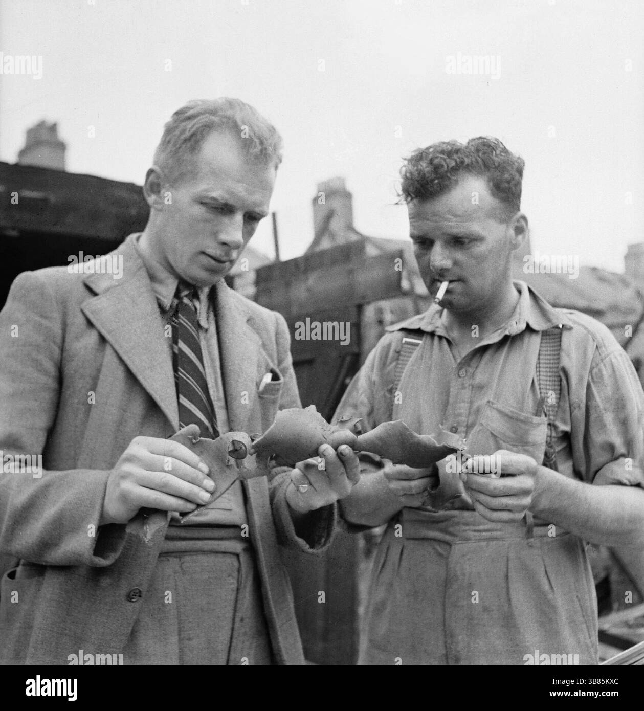 Il generale Foreman J Wigley (di Darlington) e Foreman H Uttley esaminano un pezzo dei resti di una bomba volante V1. Fanno parte di una squadra di costruttori che sono venuti a Londra da varie parti del paese per riparare i danni causati da queste bombe. Foto Stock