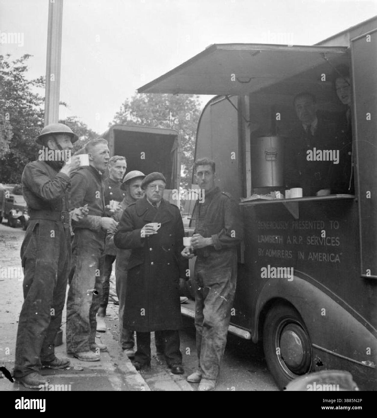 I lavoratori della difesa civile si fermano per un rinfresco durante una pausa nei lavori di soccorso accanto a una mensa dopo un attacco V1 nella zona di Highland Road e Lunham Road nell'Upper Norwood. I V-1 e V-2 erano armi spaventose, ma non ebbero alcun effetto sull'esito della guerra. Il V-1 era una bomba volante che cadde quando il carburante del suo jet si esauriva. Il V2 era un missile balistico. Entrambi sono stati ampiamente utilizzati nelle città dell'Europa occidentale. Foto Stock