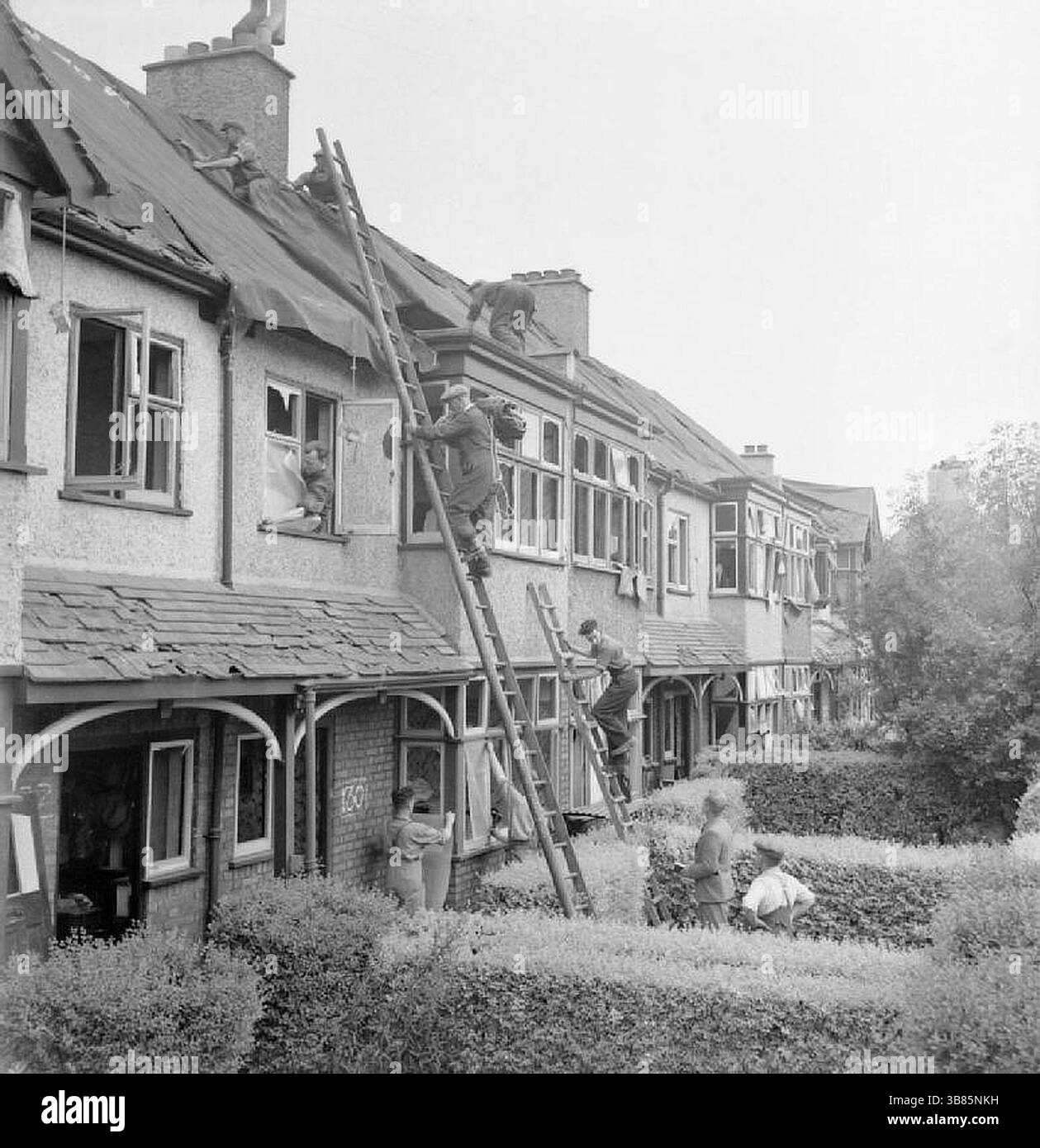 I costruttori della "Blitz Repair Squad" al lavoro su una fila di case danneggiate da una bomba volante V1, da qualche parte a Londra. La didascalia originale afferma che questo danno è tipico di un simile attacco, con piastrelle e gran parte del tetto stesso mancanti e finestre soffiate dentro. I costruttori fanno parte della "Blitz Repair Squad". Questa squadra è una squadra di costruttori che sono venuti a Londra da varie parti del paese per aiutare a riparare i danni causati dalle bombe volanti V1. Foto Stock
